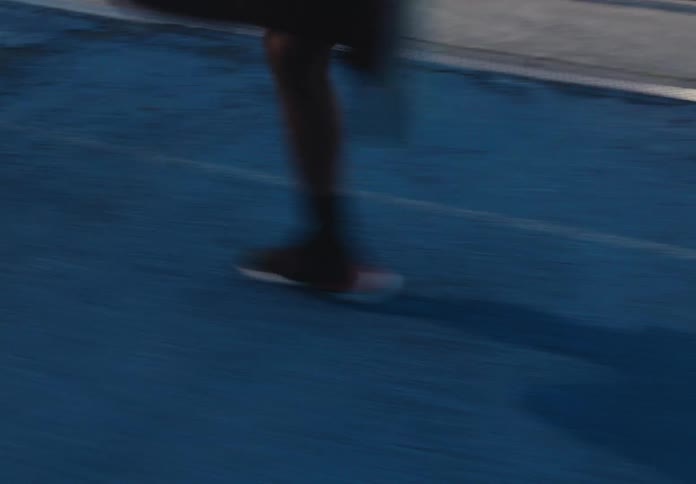 A man sprints dynamically down a blue track his motion blurred as he runs with speed and focus