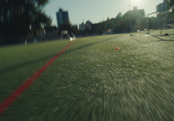 Person runs on synthetic turf beside red line on urban sports field
