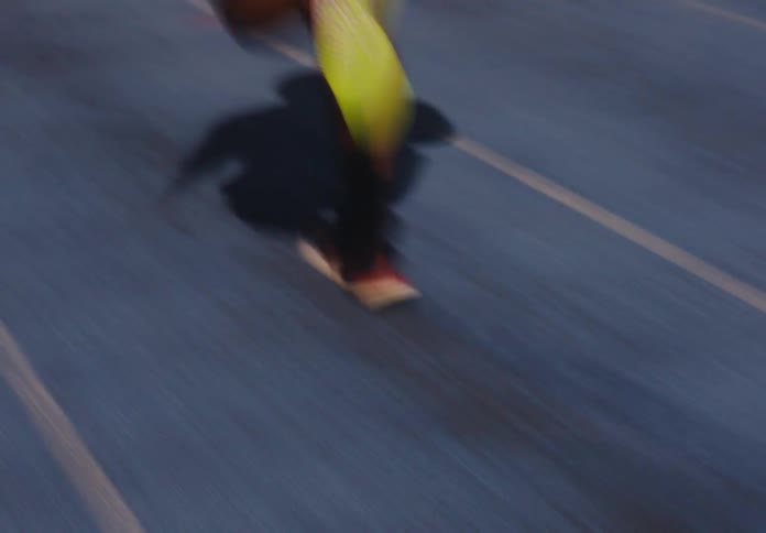 Legs in motion run along synthetic track marked by yellow lines under soft evening light