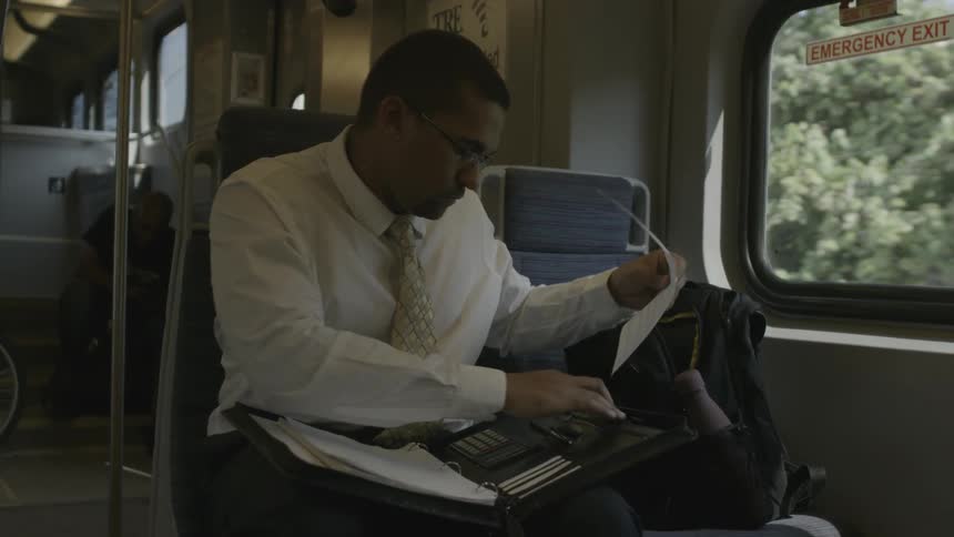 A man on a train closes up his binder and puts it in his bag