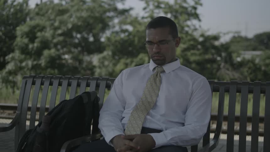 A man in a tie sits on a bench