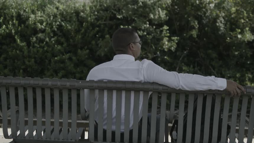 A man sits on a bench on a sunny day