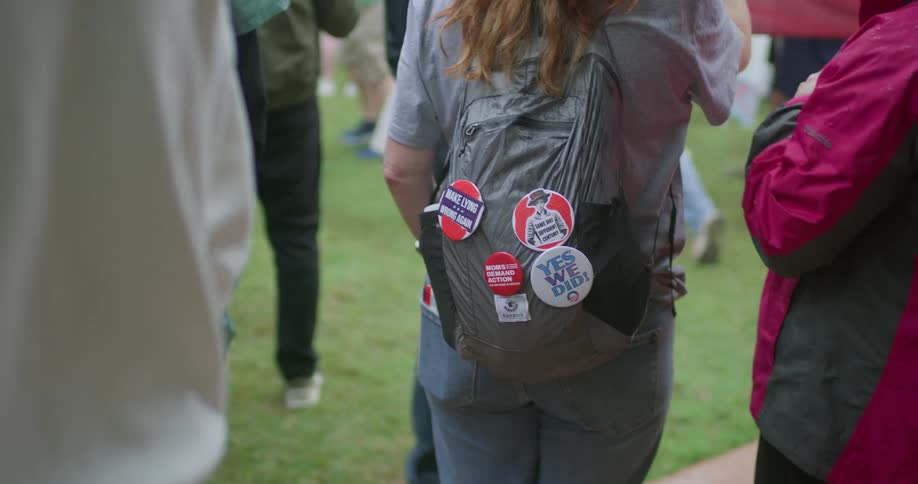 Gray backpack displays political stickers during outdoor gathering