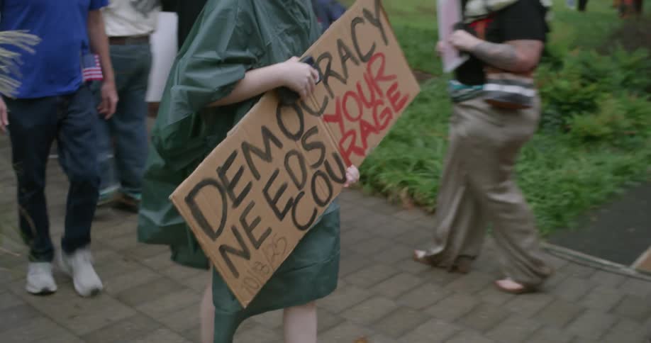 Sign reading democracy needs your courage held during public demonstration