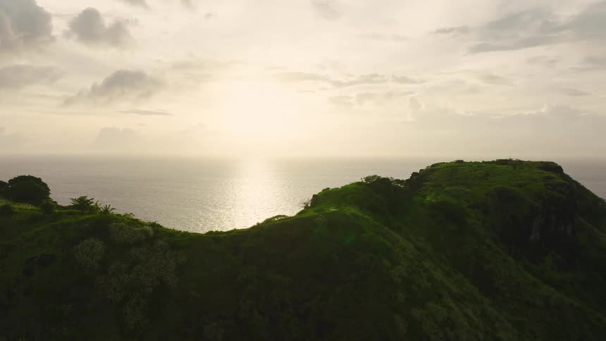 The scene presents a sharp contrast between the deep dark blue of the open ocean on the left and the vibrant lighter turquoise and green colors of an extensive shallow coral reef or sandbar on the right