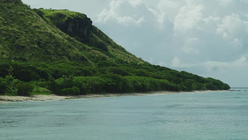 Green mountains are on the tropical island by the shore