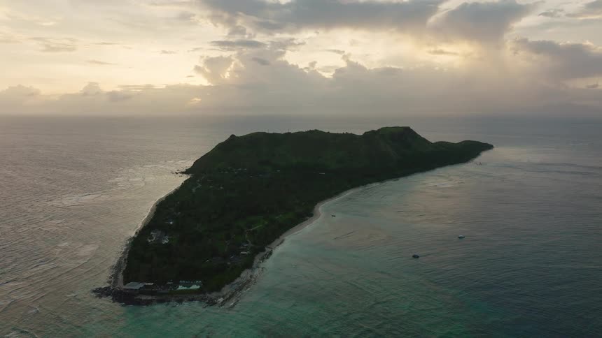 Green islet with hills in the middle of the ocean outdoors during day time