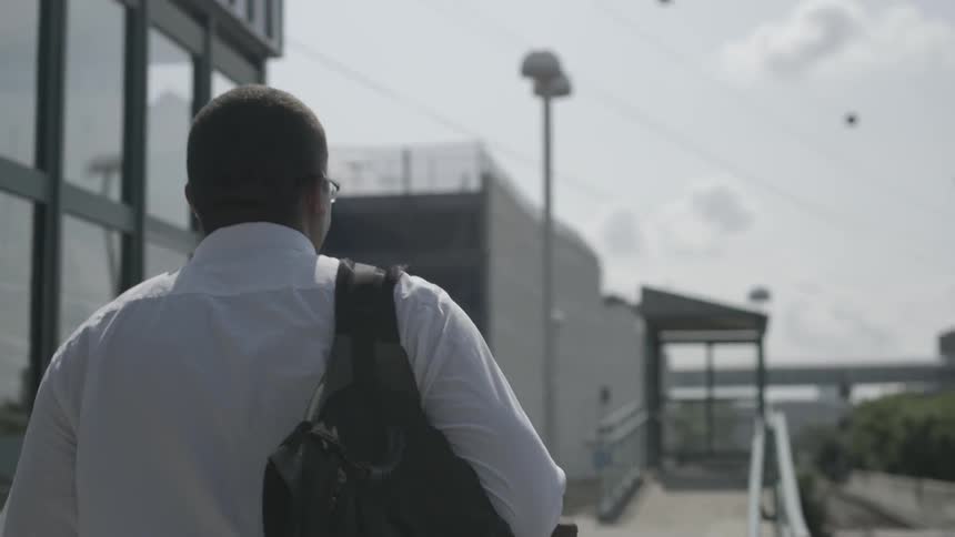 A man is walking towards buildings