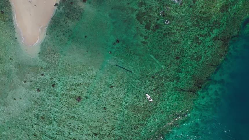 Small white boat over a reef near a beach outdoors during day time