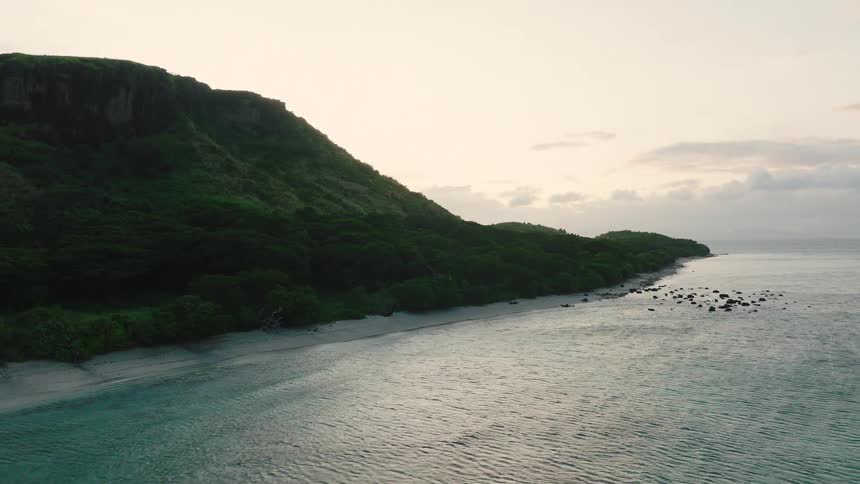 Cliff next to the ocean with a small sandy beach between them outdoors during day time