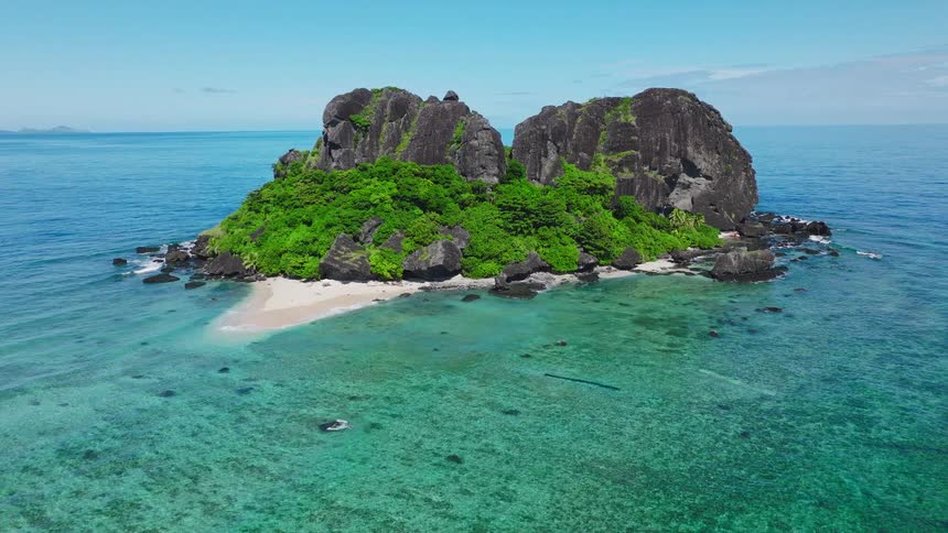 Promontory half covered in vegetation in the middle of the sea outdoors during day time