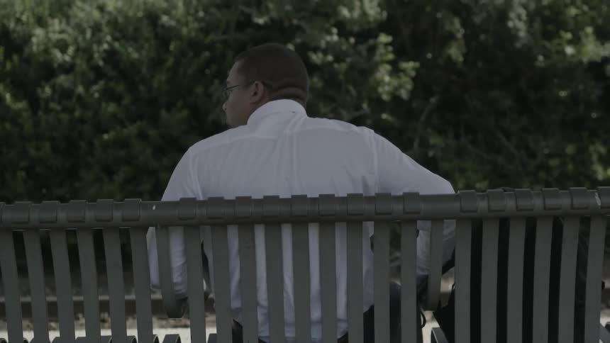 A man sits down on a park bench