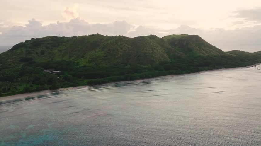 Coastal green mountain range close to the shoreline and the sea outdoors during day time