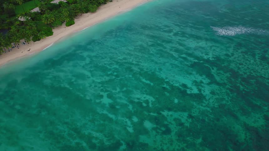 Small homes are on the shoreline of the tropical island