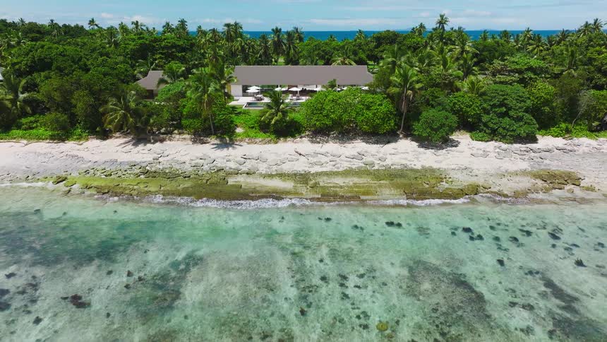 Beachfront property surrounded by palms and turquoise waters reveals serene tropical retreat