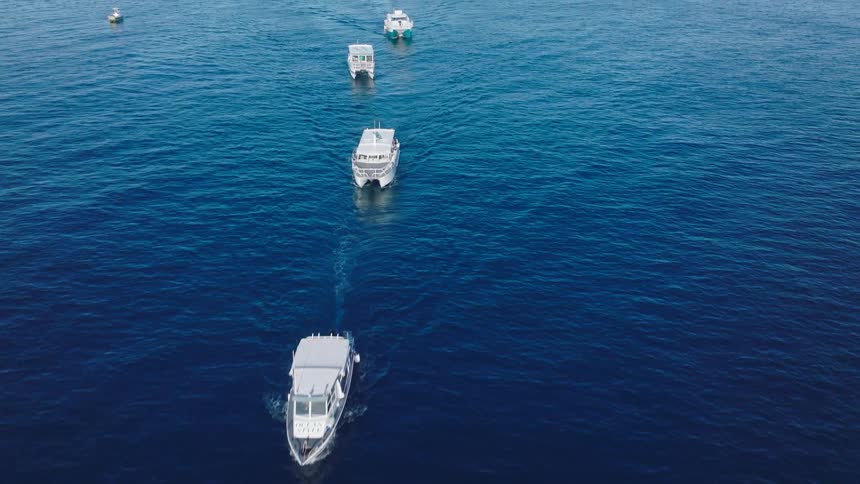 The line of boats travel away from the island