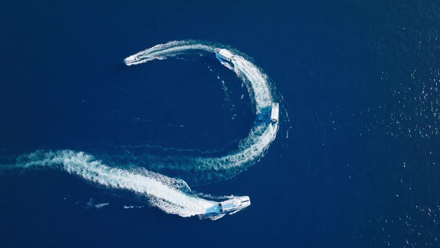 The boats leave a trail as they turn in the ocean