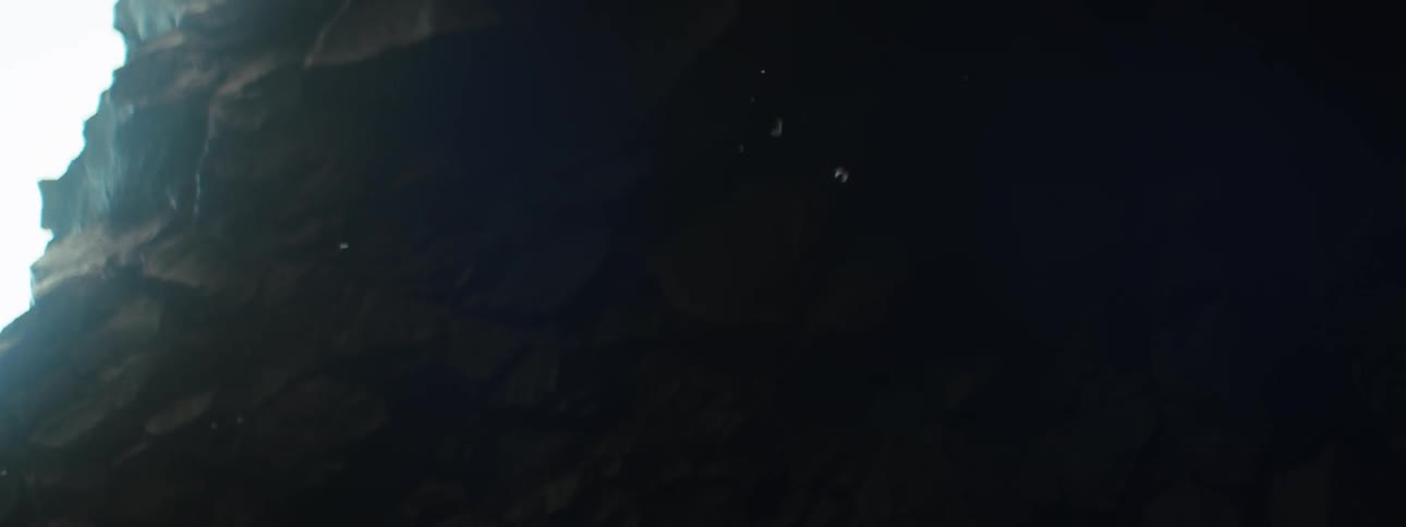 Soft light enters the cave opening revealing rocky textures amid surrounding darkness