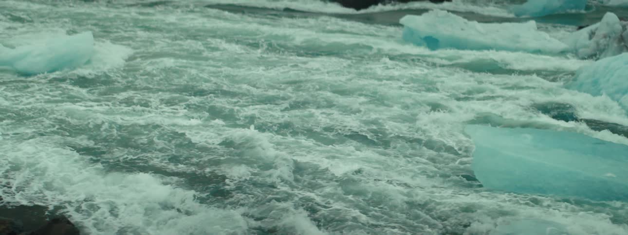 Turbulent frothing greenish blue water with pieces of ice or small icebergs