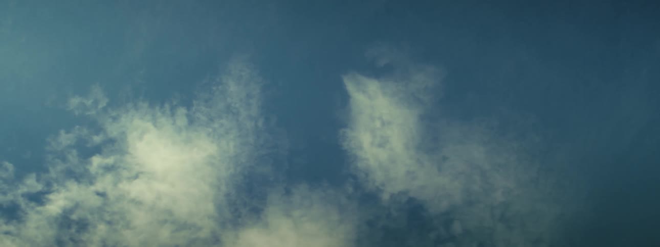 Wispy clouds are floating through a blue sky