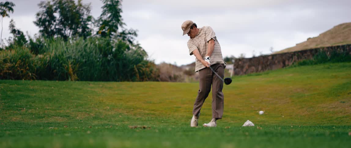 A man hitting a golf ball with a club