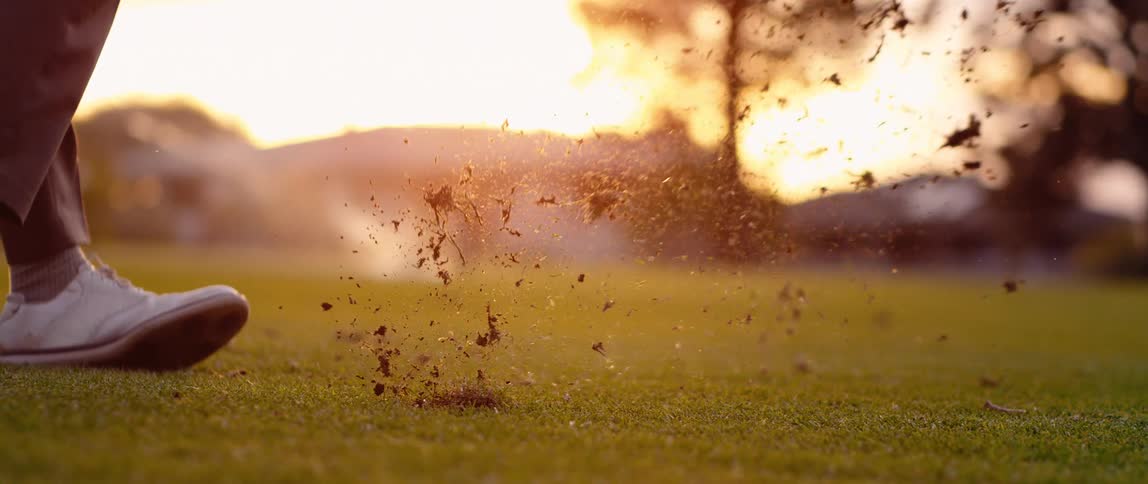 Man hits the golf ball with the golf club in the evening