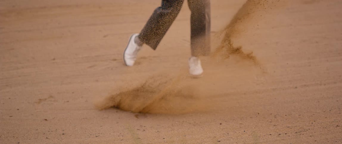 Golfer hits ball from bunker sending sand flying in a powerful and challenging shot