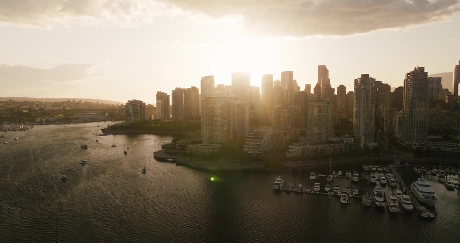 Setting sun reflects on tall buildings and boatfilled marina creating a serene urban scene