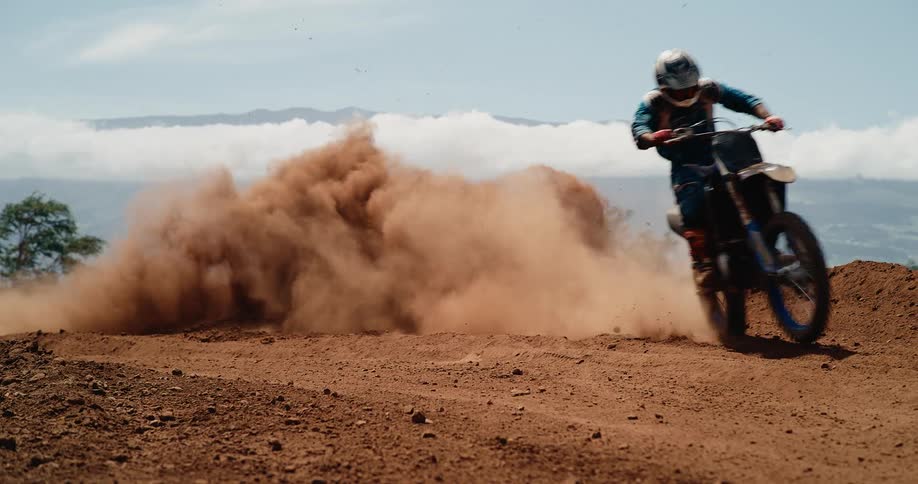 The motocross driver leaves a dust cloud as he makes a turn on the track
