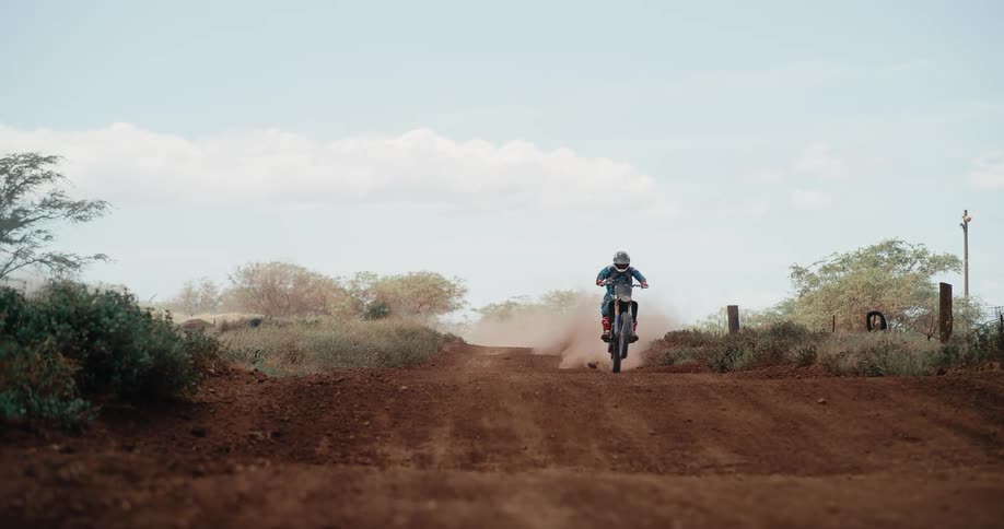 A man is riding his motorcycle on a dirt road