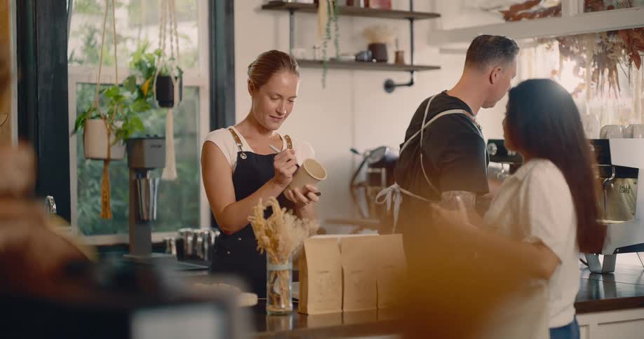 The customer is ordering with an employee in the coffee shop