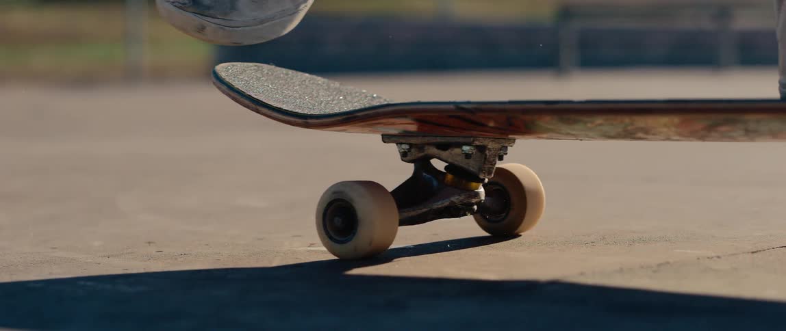 Legs of a person on a moving skateboard at daytime