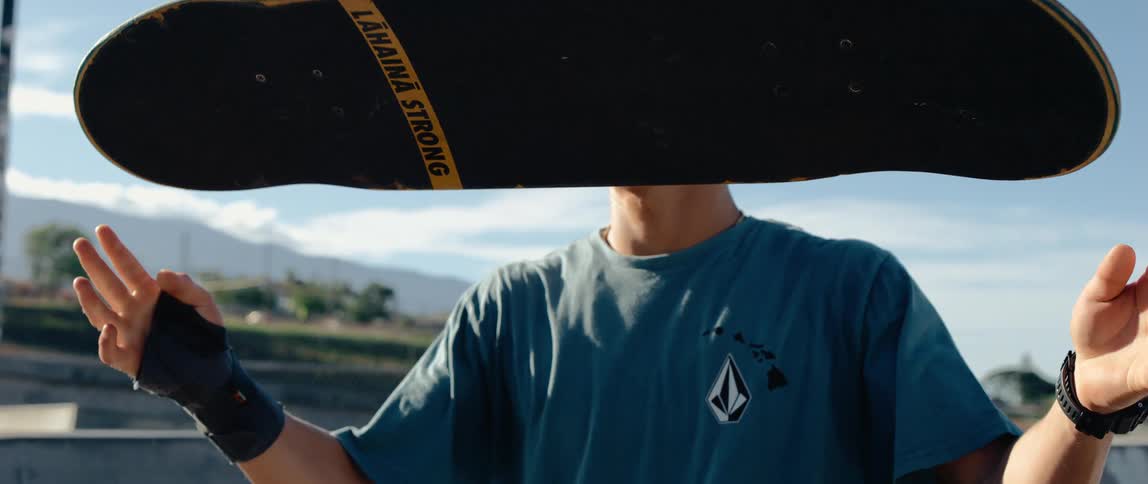 A young skateboarder flips his colorful deck between his hands in slow motion his focused gaze locked on the board