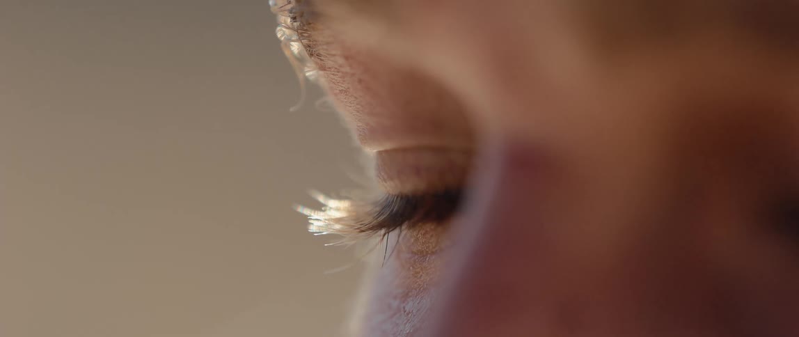 Light brown iris reflects light as eyelashes and skin reveal texture in extreme detail