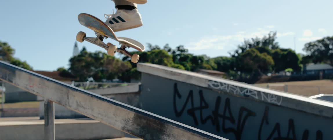 Skater performs aerial trick over metal rail in outdoor skatepark
