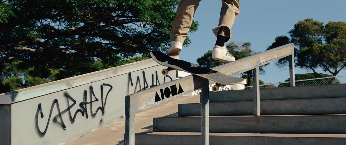 A skateboarder attempts a flip trick onto a handrail but loses balance and falls
