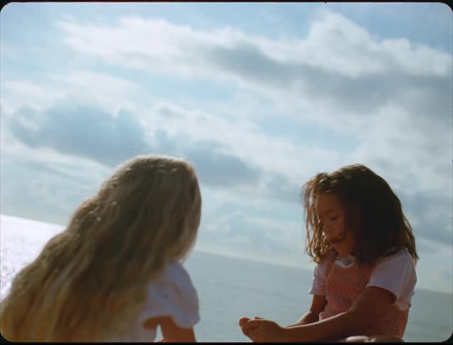 Two children sitting outdoors on a sunny day