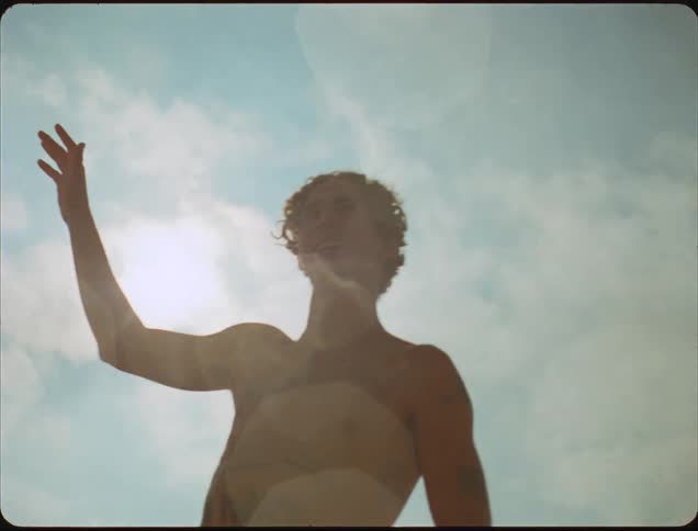 A man is playing volleyball outside in the sun