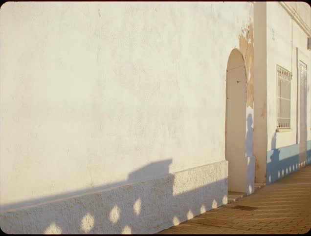 Shadow of a person cast on a light wall in the late afternoon