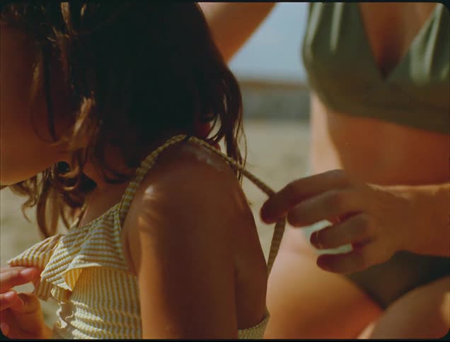 Adults hand applies sunscreen to a smiling childs shoulder