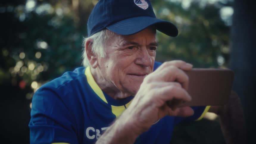 Man watches something on his phone with an intense expression