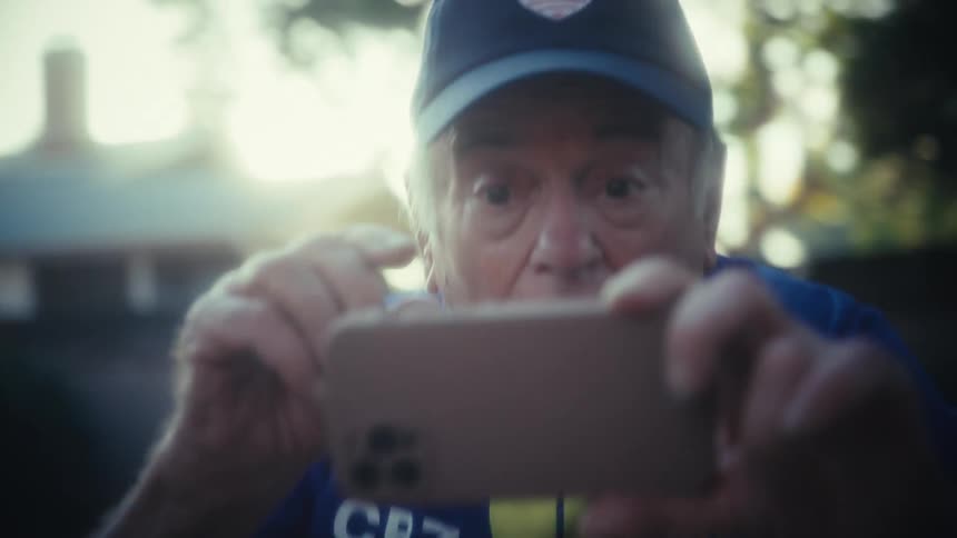 The man cheers at a sporting event on his cell phone
