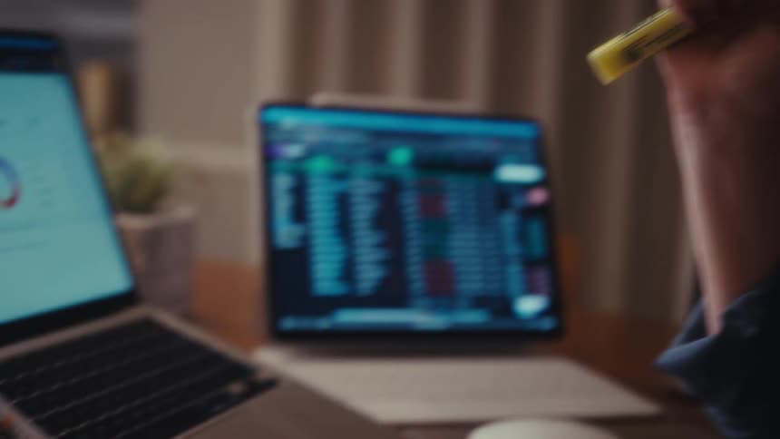 Woman analyzes a printed spreadsheet with data and colored markings in front of a laptop