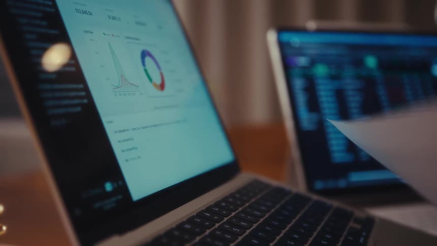 Two laptops are set up on a desk in an office