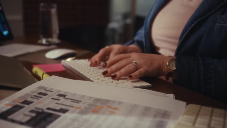 The woman types on the keyboard at her desk full of paperwork