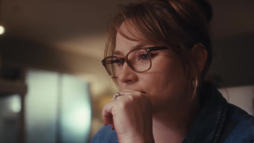 A woman sitting in an office is putting her head in her hand as she thinks
