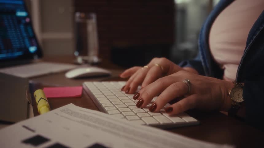 A woman is sitting at a desk typing on a keyboard for a computer