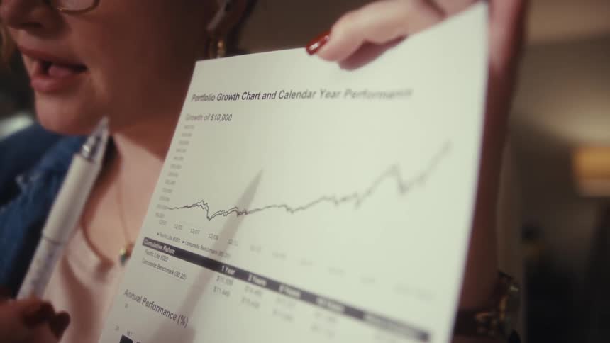 Woman presenting a printed financial performance chart