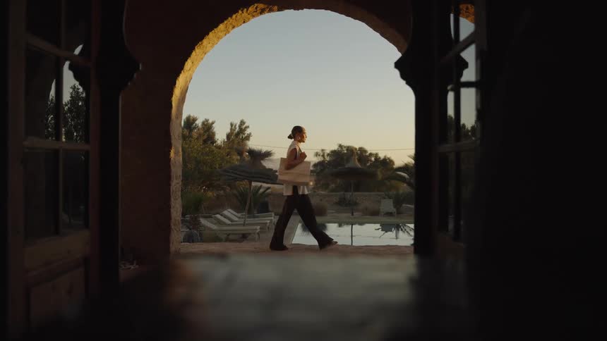 The woman walks past the pool in the resort