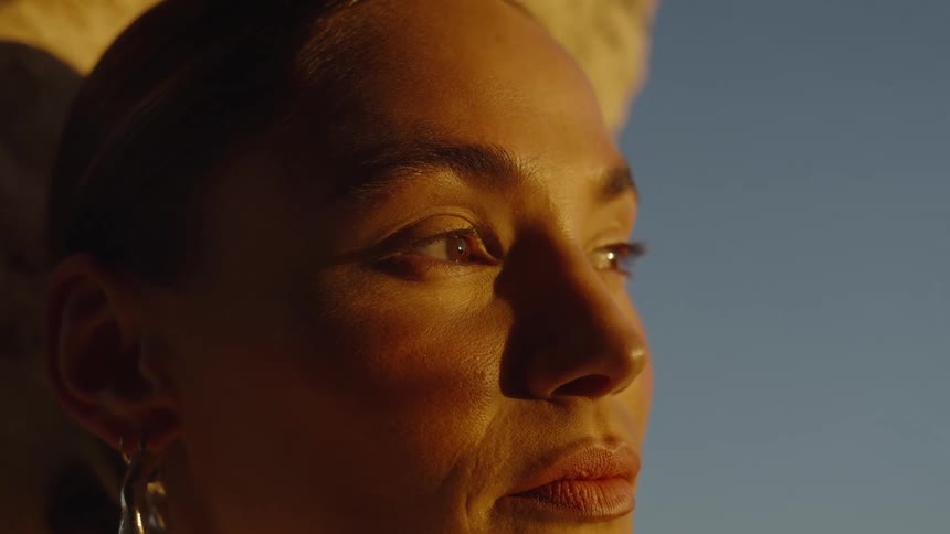 Woman wearing earrings with golden sunlight over her face outdoors during dusk or dawn